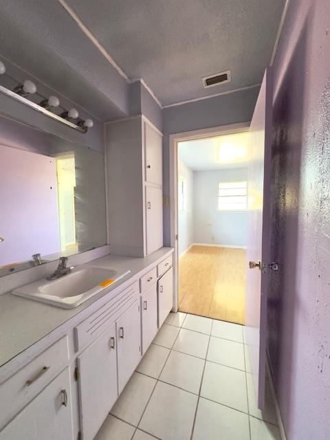 bathroom with tile patterned floors, vanity, and a textured ceiling