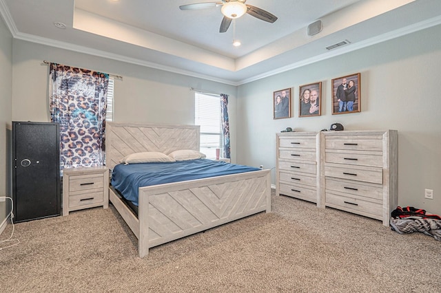 bedroom featuring ornamental molding, light carpet, ceiling fan, and a tray ceiling