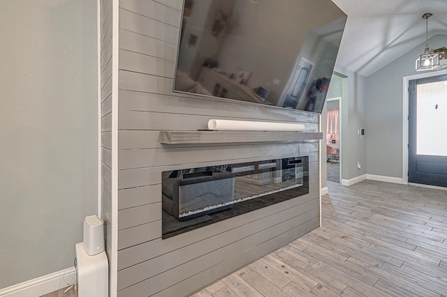 kitchen with vaulted ceiling, a multi sided fireplace, light hardwood / wood-style floors, and pendant lighting