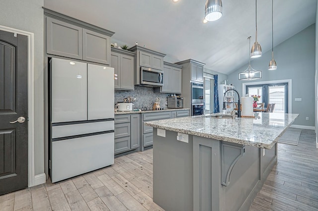 kitchen with sink, appliances with stainless steel finishes, gray cabinetry, a kitchen bar, and vaulted ceiling