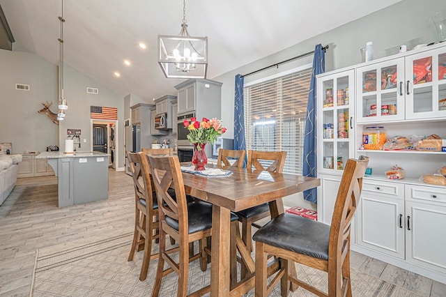 dining area featuring vaulted ceiling, a notable chandelier, and light hardwood / wood-style floors