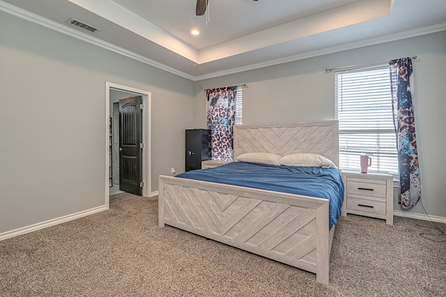 carpeted bedroom featuring multiple windows, a tray ceiling, crown molding, and ceiling fan