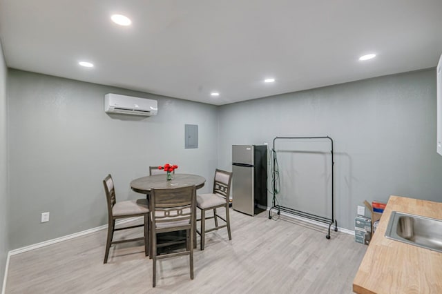 dining space featuring light wood-type flooring, electric panel, and a wall unit AC