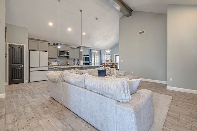 living room with beamed ceiling, high vaulted ceiling, and light hardwood / wood-style flooring