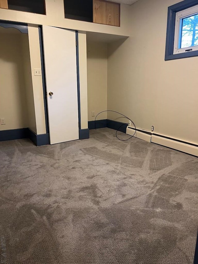 carpeted empty room with a baseboard radiator