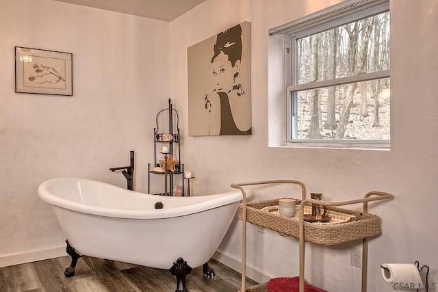 bathroom featuring a freestanding tub, baseboards, and wood finished floors