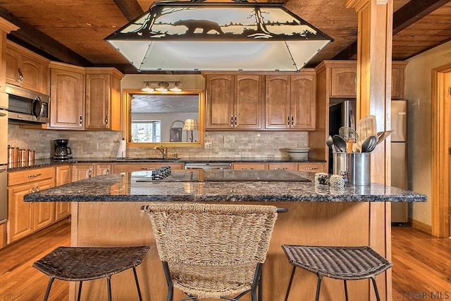 kitchen featuring a breakfast bar, decorative backsplash, appliances with stainless steel finishes, and a sink