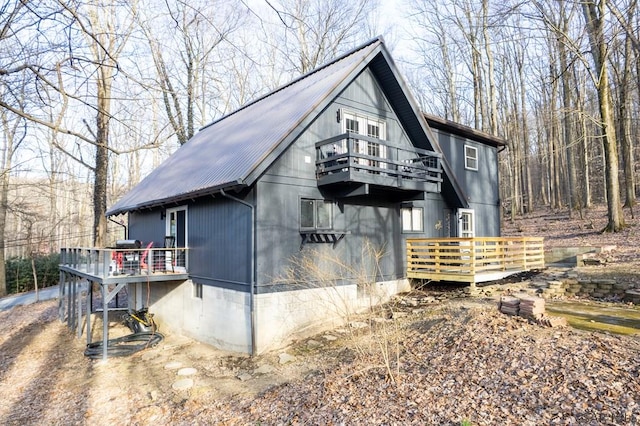 view of home's exterior with metal roof, a balcony, and a deck