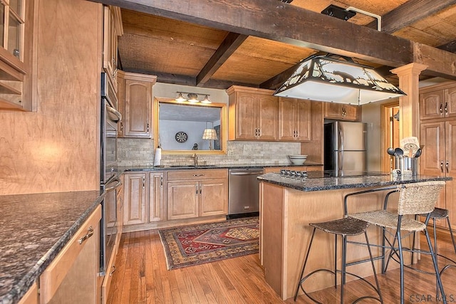 kitchen with beam ceiling, dark wood-type flooring, a center island, stainless steel appliances, and a breakfast bar area