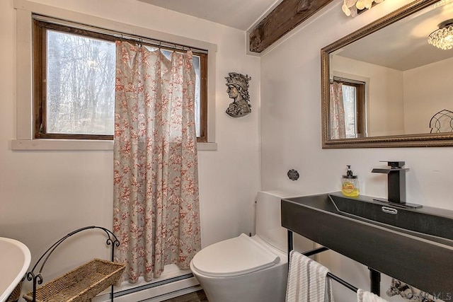 bathroom with a baseboard heating unit, toilet, a shower with curtain, and a sink