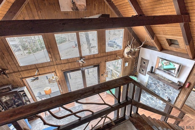 stairs featuring beamed ceiling, wood walls, wooden ceiling, and high vaulted ceiling