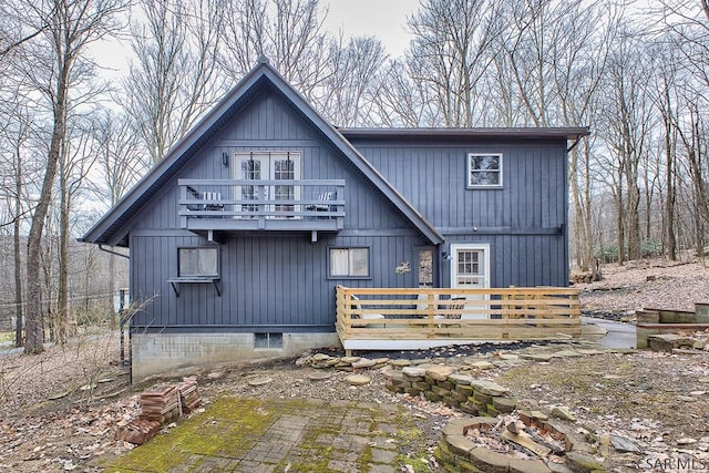 back of house with a wooden deck, a fire pit, and a balcony