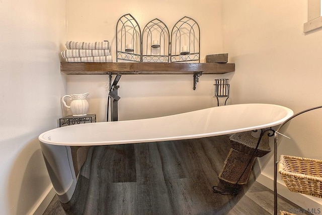 details featuring baseboards, a soaking tub, and wood finished floors