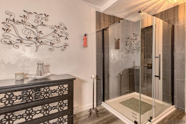 bathroom featuring baseboards, wood finished floors, and a stall shower