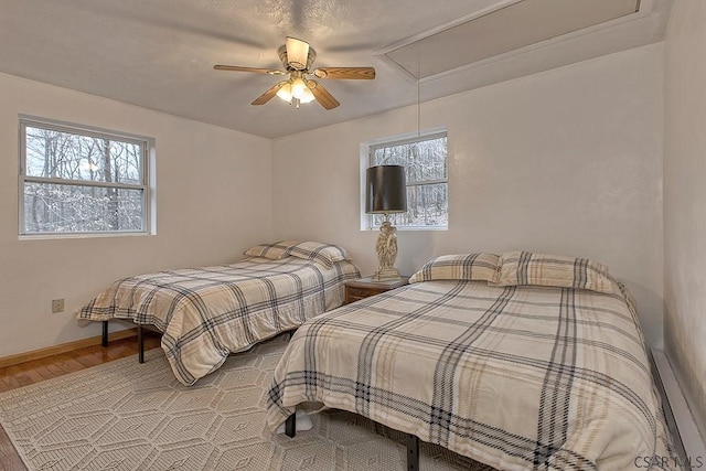 bedroom featuring baseboards, multiple windows, attic access, and wood finished floors