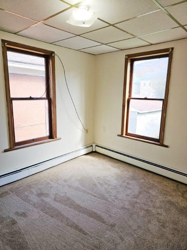 carpeted spare room with a drop ceiling and plenty of natural light