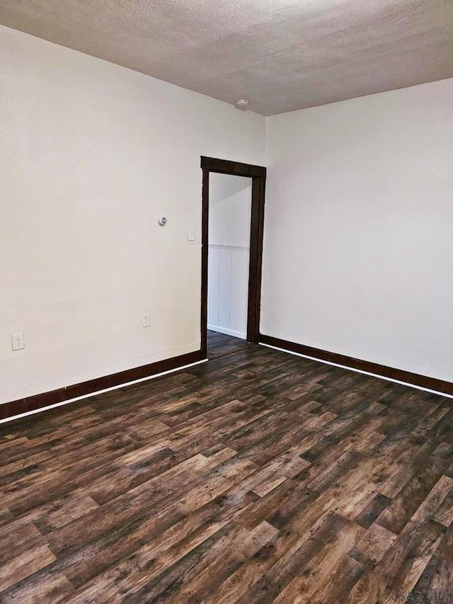 unfurnished room with dark wood-style floors, a textured ceiling, and baseboards