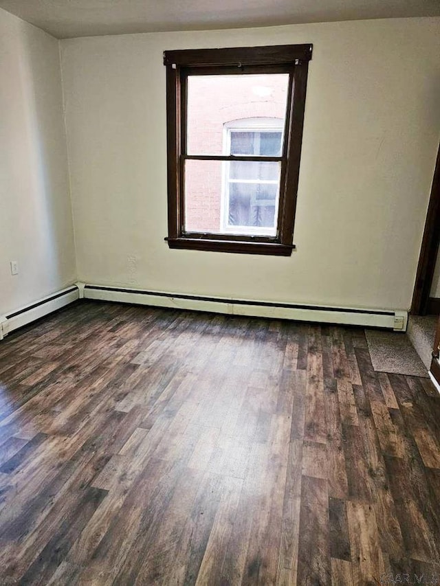 unfurnished room featuring baseboard heating and wood finished floors