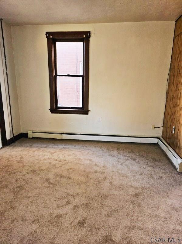 unfurnished room featuring a textured ceiling, baseboard heating, and carpet