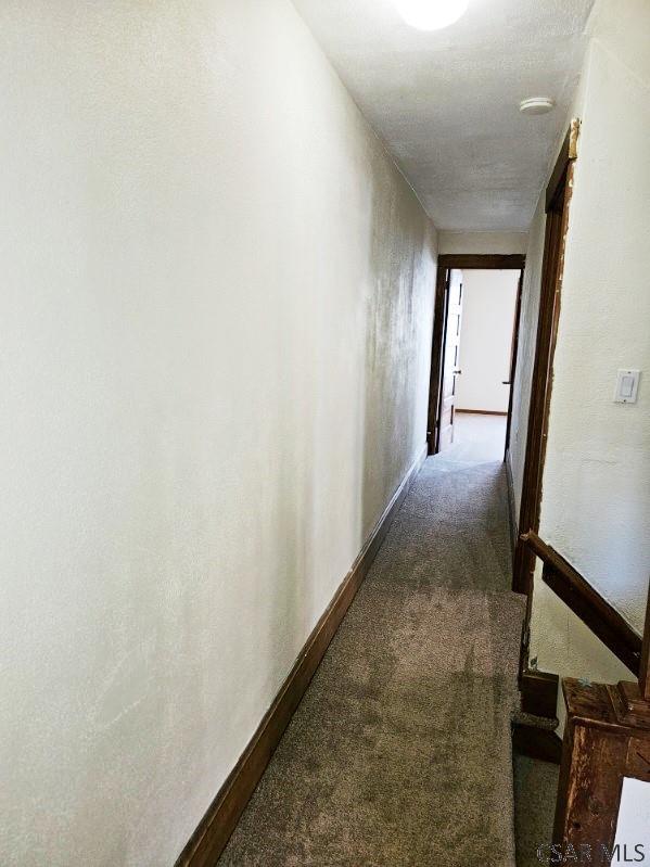 hallway featuring carpet and baseboards