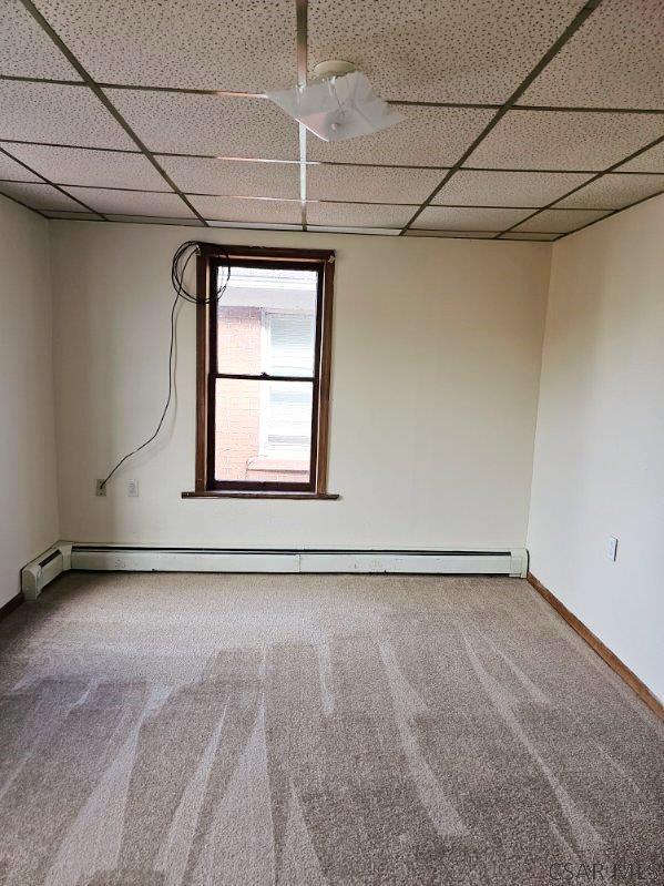 spare room featuring carpet floors, baseboards, and a drop ceiling