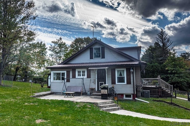 view of front of property with fence, metal roof, a patio, and a front yard