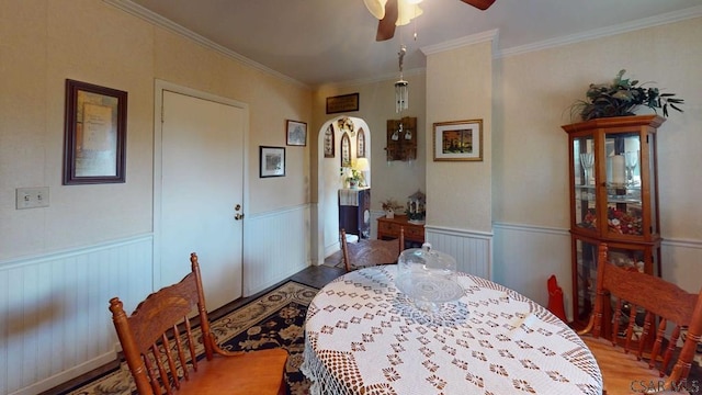 dining room with a wainscoted wall, ceiling fan, and crown molding