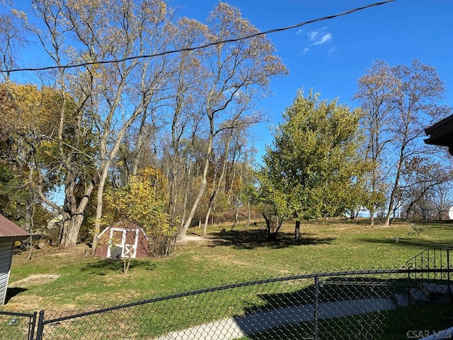 view of yard featuring an outbuilding, fence, and a storage shed