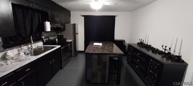 kitchen featuring stainless steel appliances, dark cabinetry, under cabinet range hood, concrete floors, and a sink