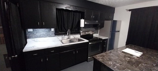 kitchen with appliances with stainless steel finishes, dark cabinets, a sink, and under cabinet range hood