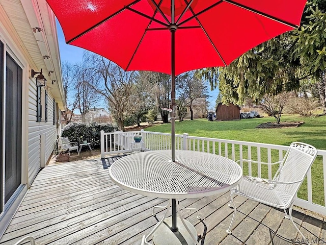 wooden deck with outdoor dining space and a lawn