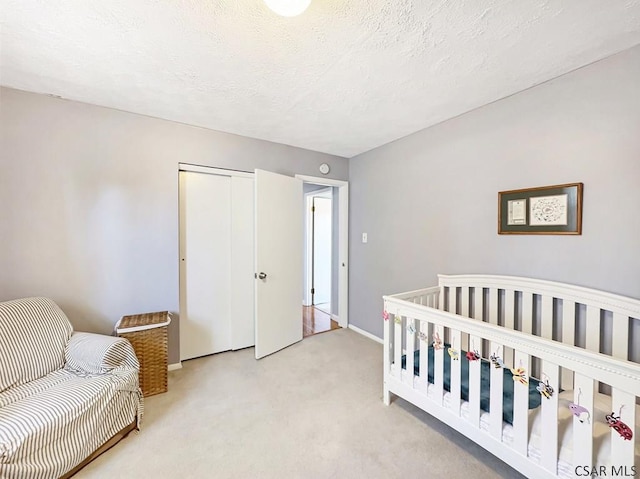 bedroom with a closet, carpet flooring, a textured ceiling, and baseboards