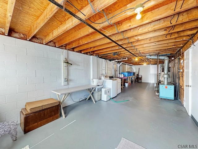 unfinished below grade area featuring concrete block wall and washing machine and clothes dryer