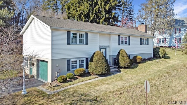 bi-level home featuring a front lawn, a garage, driveway, and a chimney