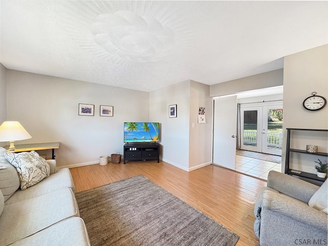 living area with wood finished floors, baseboards, and french doors