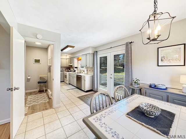 dining area with an inviting chandelier, light tile patterned floors, french doors, and baseboards