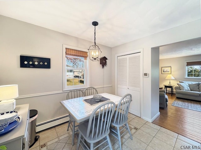 dining room with a baseboard heating unit, an inviting chandelier, light tile patterned floors, and baseboards