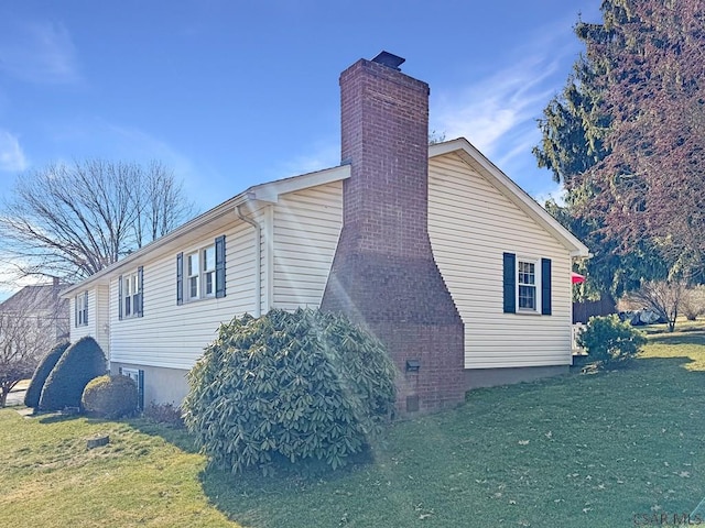 view of side of property with a chimney and a yard