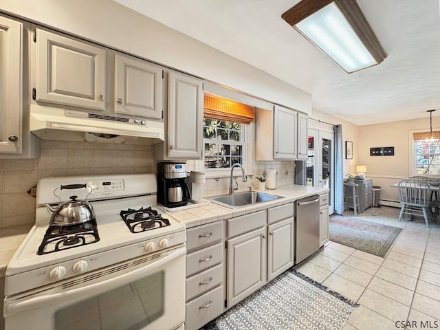 kitchen with under cabinet range hood, a sink, gas range gas stove, stainless steel dishwasher, and tasteful backsplash