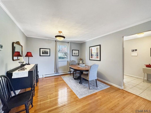 dining room with a baseboard heating unit, crown molding, light wood-style flooring, and baseboards