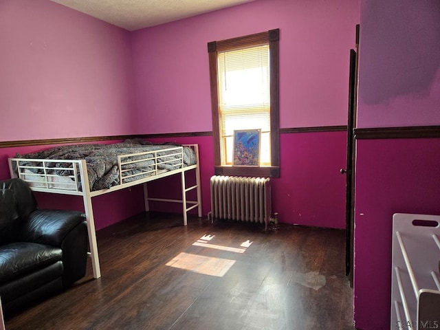 unfurnished bedroom featuring radiator and dark hardwood / wood-style floors