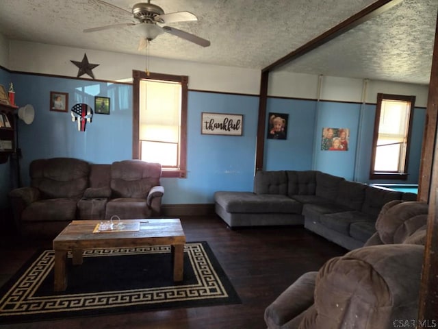 living room featuring ceiling fan, dark wood-type flooring, and a textured ceiling