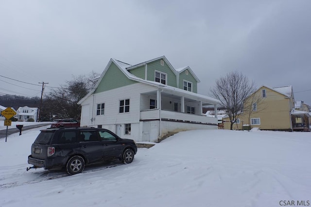 snow covered property with covered porch