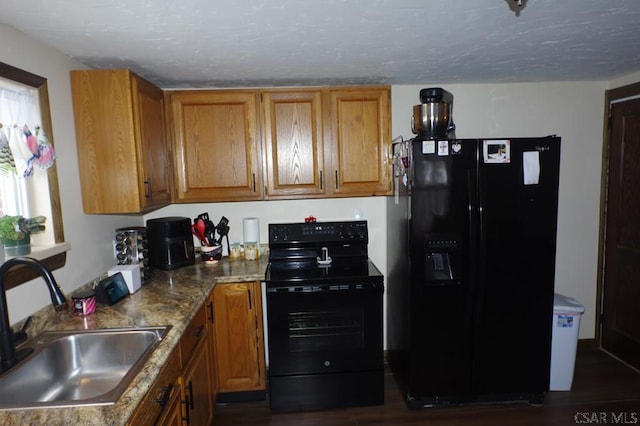 kitchen featuring sink, dark wood-type flooring, black appliances, light stone countertops, and a textured ceiling