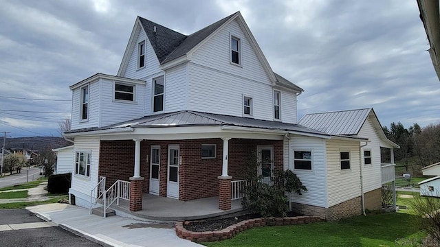 216 W Main St, Stoystown, PA 15563 - view of front of home featuring brick siding, a porch, metal roof, and a front lawn