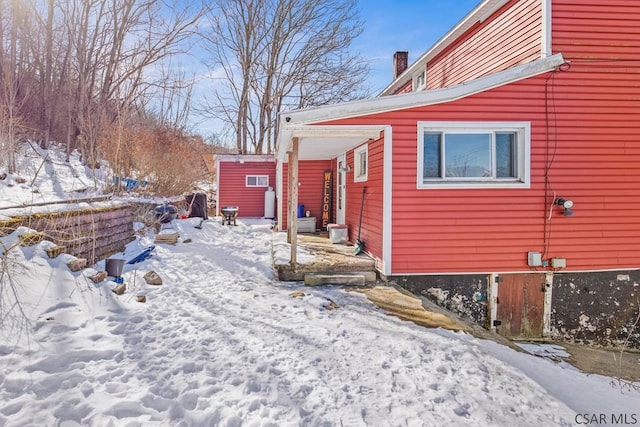 snow covered property with a chimney