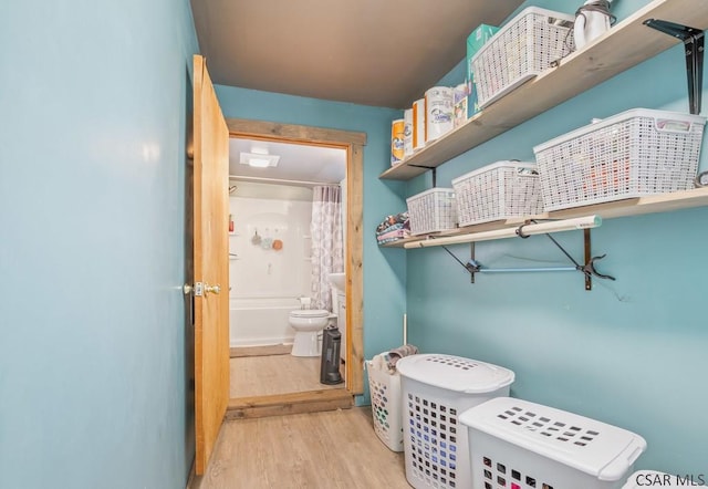 interior space with shower / bath combo with shower curtain, toilet, and wood finished floors