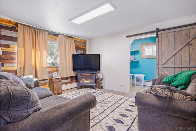 living room with a barn door, baseboard heating, wood finished floors, and a healthy amount of sunlight