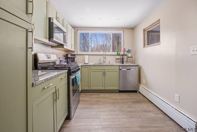 kitchen with stainless steel appliances, light wood-style flooring, green cabinets, a baseboard heating unit, and a sink