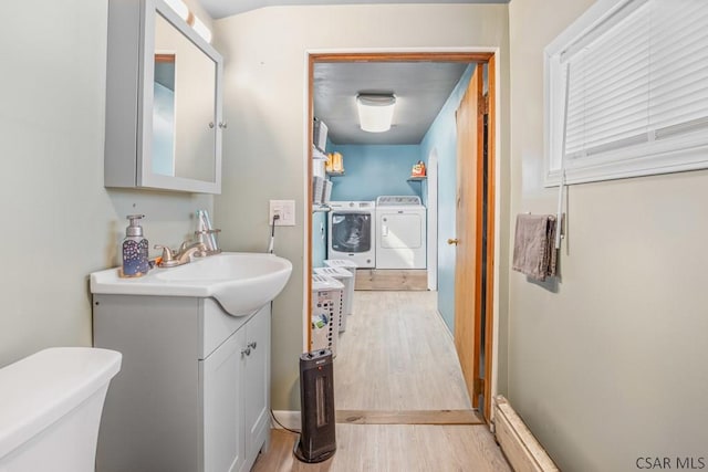 bathroom with toilet, vanity, wood finished floors, and washing machine and clothes dryer